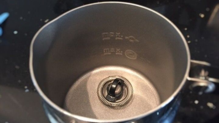 Ein Milchsch&auml;umer steht in einer modernen K&uuml;che. Das gl&auml;nzende Edelstahlgef&auml;&szlig; zeigt den runden Auslauf, der f&uuml;r das Sch&auml;umen von Milch dient.