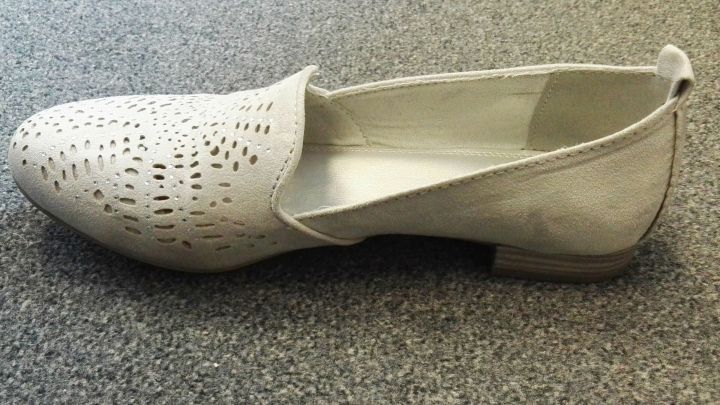 Ein eleganter Schuh mit durchbrochenem Design liegt auf einer grauen Oberfl&auml;che, perfekt f&uuml;r den modischen Alltag.