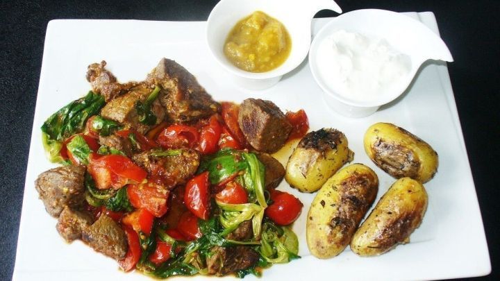 Warmer Steaksalat mit Thymiankartoffeln pr&auml;sentiert gegrilltes Fleisch, frisches Gem&uuml;se und aromatische Beilagen auf einem wei&szlig;en Teller.