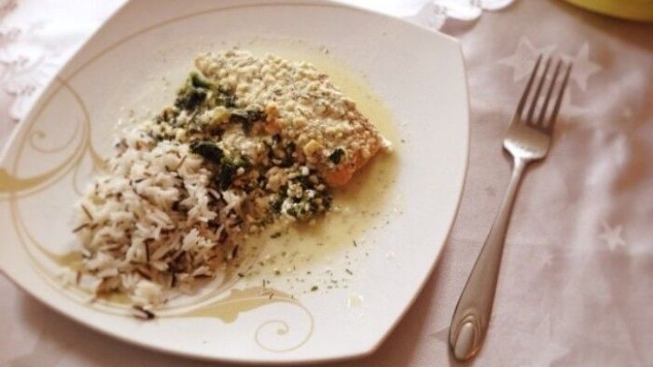 Ein gegrilltes Wildlachsfilet liegt auf einem Bett aus Spinat und wei&szlig;em Reis, serviert auf einem eleganten Teller.