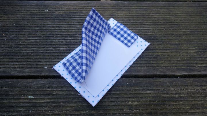 Eine Einladungskarte f&uuml;r eine &Uuml;bernachtungsparty liegt auf einem Holzuntergrund, das blaue Karomuster zieht die Blicke an.