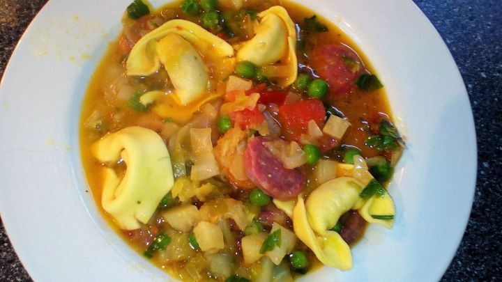 Ein bunter Kohl-Eintopf mit Nudeln wird in einer wei&szlig;en Schale serviert, umgeben von einer herzhaften Br&uuml;he und frischem Gem&uuml;se.