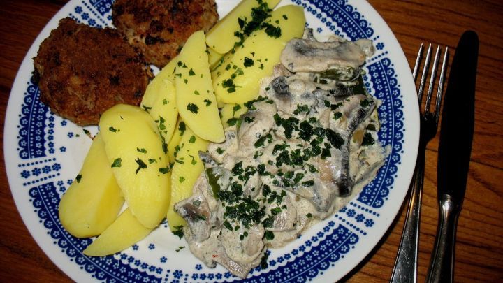 Eine bunte Platte zeigt cremige Sahne-Champignons mit Bratpaprika, umgeben von Kartoffeln und Kroketten, h&uuml;bsch garniert.
