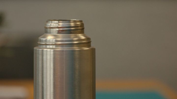 Eine Edelstahl-Thermoskanne steht auf einem Tisch, bereit zum Reinigen mit Geschirrsp&uuml;lpulver.