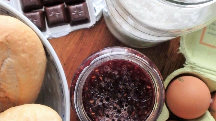 Schokolade, Eier und Marmelade liegen auf einem Holzbrett, bereit f&uuml;r die Zubereitung eines leckeren Schoko-Himbeer-Nachtischs.