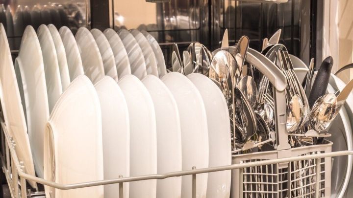 Saubere Teller und Besteck befinden sich in einem Geschirrsp&uuml;ler, der geschlossen ist und m&ouml;glicherweise einen unangenehmen Geruch abgibt.