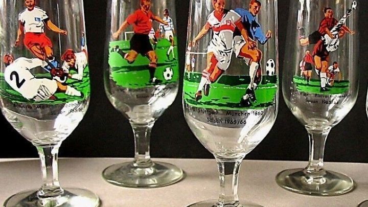 F&uuml;nf Weingl&auml;ser stehen in einer Reihe, jedes mit einem Fu&szlig;ballspieler in Aktion auf einem gr&uuml;nen Feld verziert.