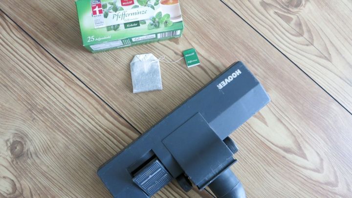 Ein Staubsauger liegt auf einem Holzboden, daneben ein Produkt zur Geruchskontrolle f&uuml;r staubfreies Saugen.