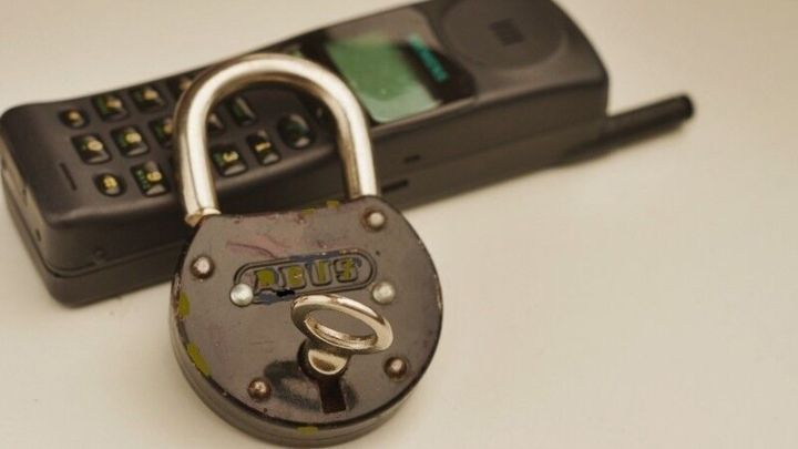 Ein Schloss liegt auf einem Telefon, um das Konzept der Mailbox-Sperrung zu verdeutlichen.