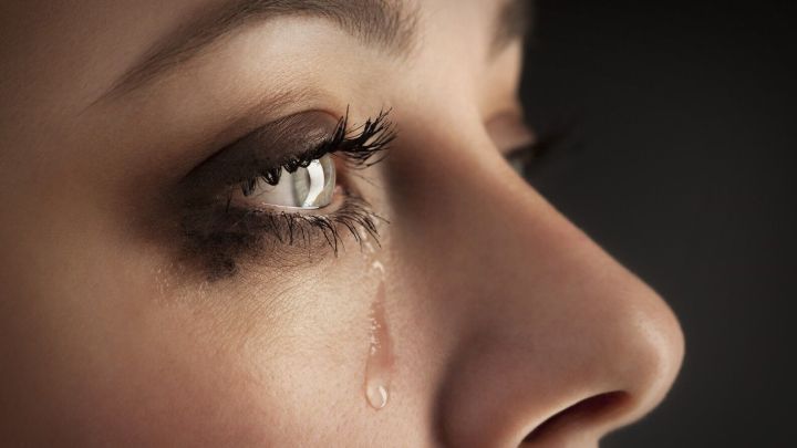 Eine Frau mit tearem&ouml;chtigen Augen blickt nachdenklich zur Seite, w&auml;hrend eine Tr&auml;ne &uuml;ber ihre Wange l&auml;uft.