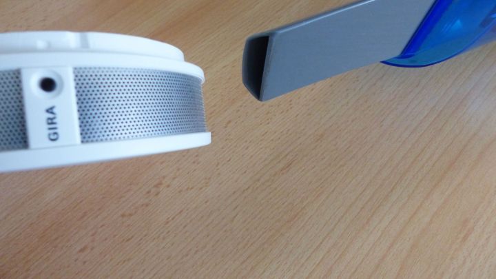 Ein Rauchmelder liegt auf einem Tisch und wird mit einem Staubtuch gereinigt, um die Effizienz zu steigern und Geld zu sparen.