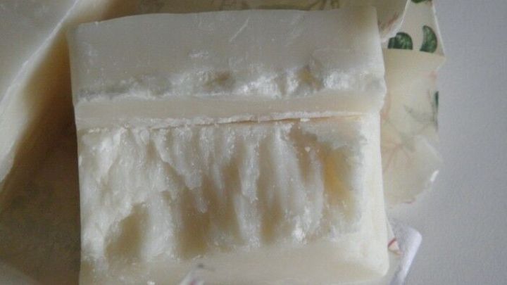 Ein St&uuml;ck Seife liegt auf einer Unterlage, w&auml;hrend es vorsichtig geschnitten wird, um Br&uuml;che zu vermeiden.