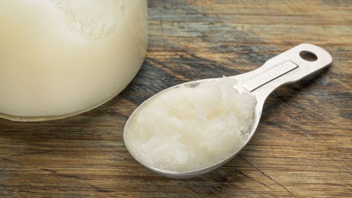 Ein Essl&ouml;ffel mit einer hellen Paste liegt auf einem Holztisch neben einem Glas. Diese Mischung k&ouml;nnte helfen, M&uuml;ckenstiche zu verhindern.