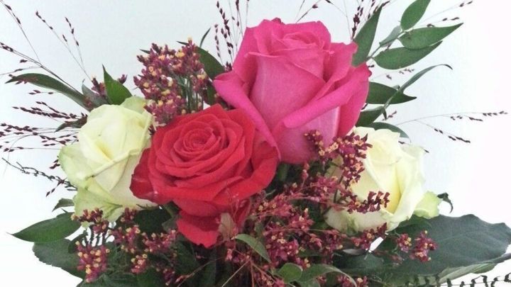 Ein bunter Blumenstrau&szlig;, bestehend aus roten, wei&szlig;en und pinken Rosen, schm&uuml;ckt einen Tisch und bringt Freude in den Raum.