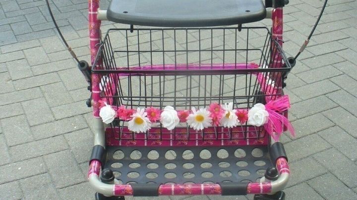 Ein bunter Rollator steht auf einem Pflasterweg, geschm&uuml;ckt mit Blumen und bunten B&auml;ndern, welche Lebensfreude ausstrahlen.