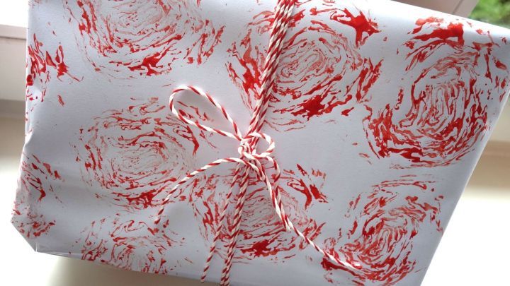 Ein kreativ bedrucktes Papier zeigt rote Radicchio-Rosenstempel in einem dekorativen Muster, liebevoll mit einer Schnur gebunden.