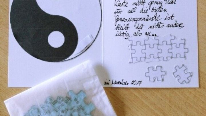 Eine Genesungskarte zeigt das Yin-Yang-Symbol, daneben liegt ein Beutel mit Puzzlest&uuml;cken und handgeschriebener Nachricht.