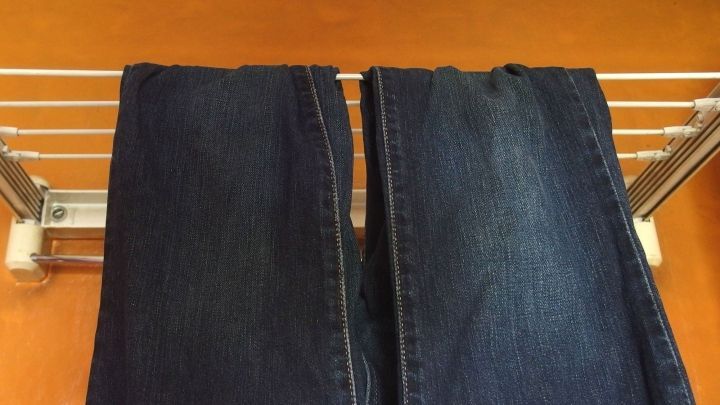 Zwei Hosen h&auml;ngen ordentlich an einer W&auml;scheleine ohne Klammern, auf einem hellen Hintergrund, zum Trocknen.