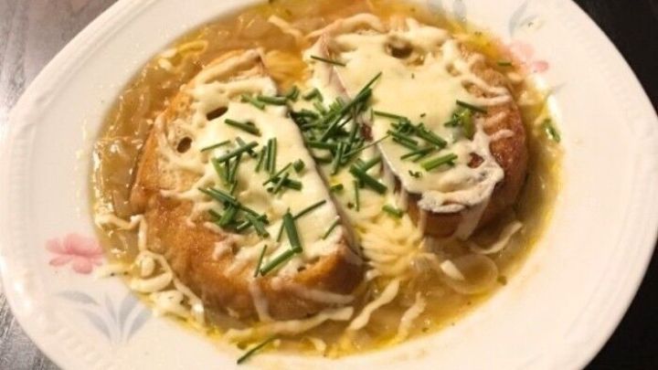 Eine deftige franz&ouml;sische Zwiebelsuppe mit R&ouml;stbaguette Einlage wird serviert, &uuml;berbacken und garniert mit frischem Schnittlauch.