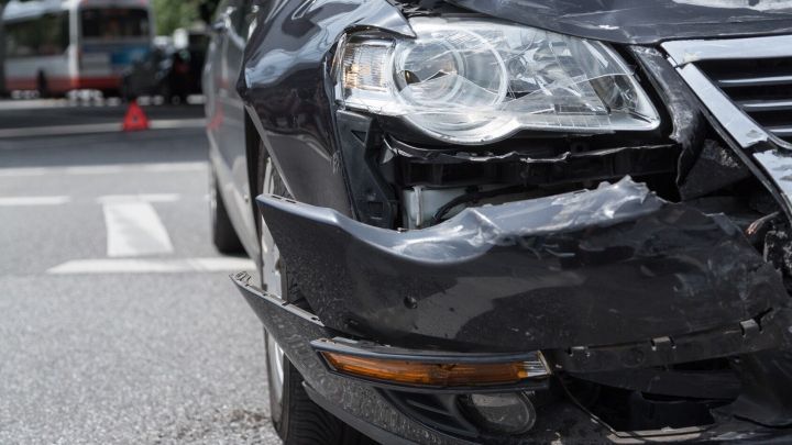 Ein besch&auml;digtes Auto steht in einer urbanen Umgebung, wobei der Unfall Schaden an der Kfz-Versicherung verdeutlicht.