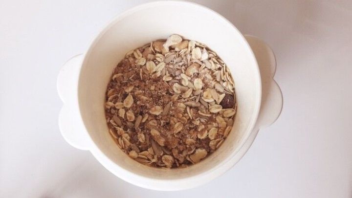 Eine Sch&uuml;ssel mit M&uuml;sli steht auf einem Tisch, gef&uuml;llt mit Haferflocken und Schokoladenst&uuml;ckchen, bereit zum Genie&szlig;en.