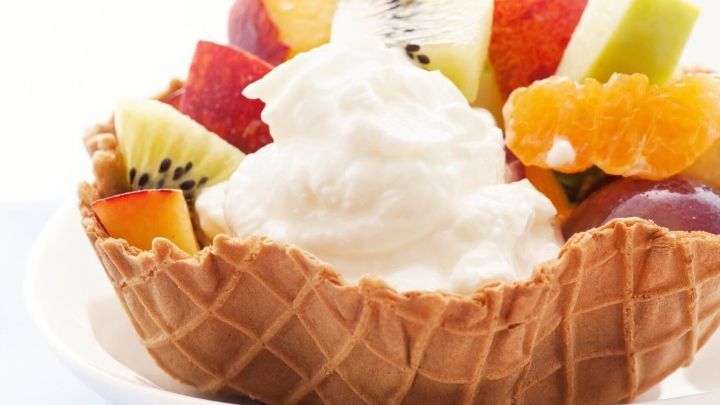 Eine Waffelschale ist gef&uuml;llt mit frischen Fr&uuml;chten und einer gro&szlig;z&uuml;gigen Portion Sahne, perfekt f&uuml;r ein schnelles Dessert.