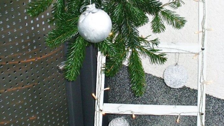 Eine wei&szlig;e Leiter ist mit Tannenzweigen, Sternen und Kugeln dekoriert und steht an einer Wand im Eingangsbereich.