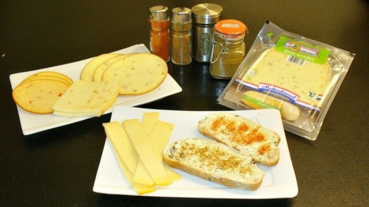 K&auml;sebrote mit verschiedenen K&auml;sesorten und Gew&uuml;rzen liegen auf Tellern, bereit zum Zubereiten.