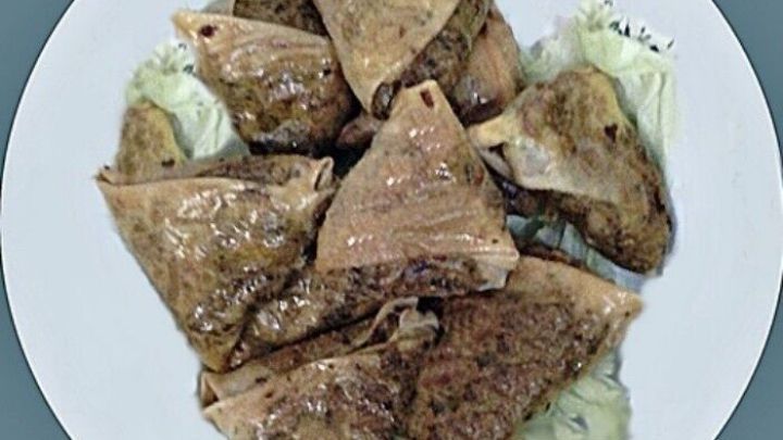 Gef&uuml;llte Teigtaschen liegen auf einem wei&szlig;en Teller und wirken k&ouml;stlich, umgeben von einem schlichten Hintergrund.