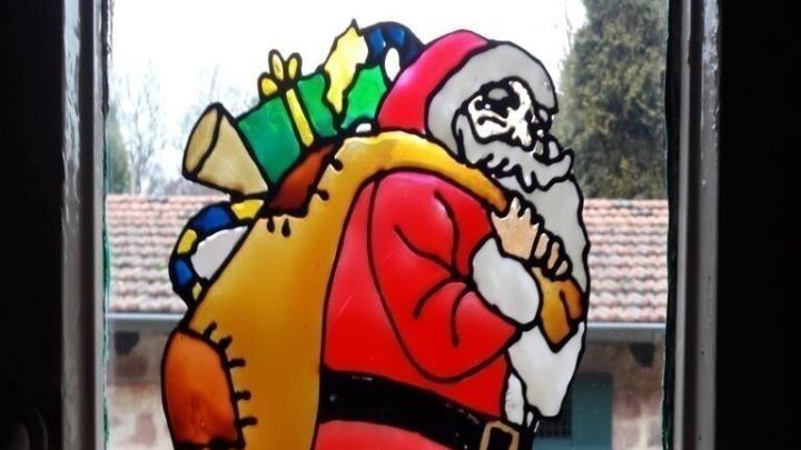 Ein bunter Weihnachtsmann mit Geschenken im Sack h&auml;ngt an einem Fenster und sorgt f&uuml;r festliche Stimmung im Raum.