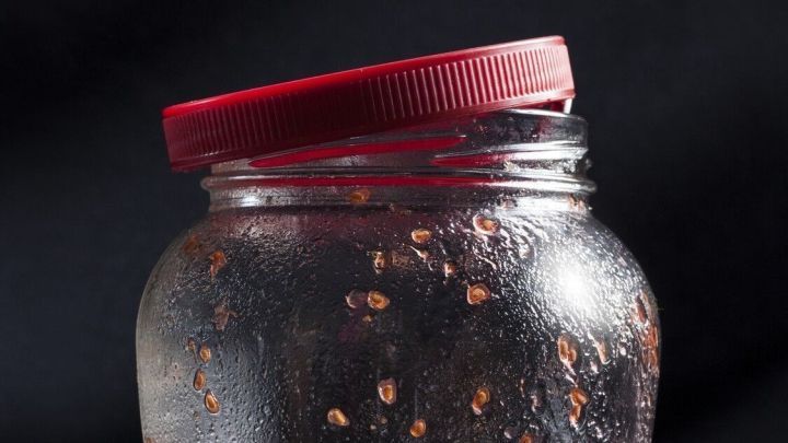 Ein Glas mit Marmeladeresten steht auf einem dunklen Untergrund, es ist teils beschlagen und zeigt Reste der Marmelade.