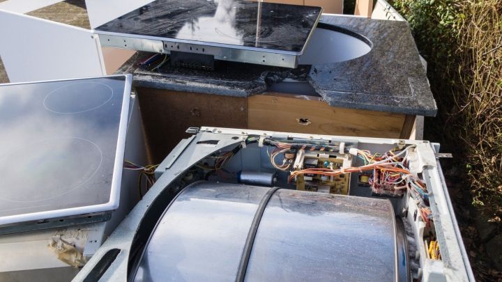 Eine kaputte Waschmaschine liegt offen, umgeben von anderen Haushaltsger&auml;ten, und wartet auf eine sinnvolle Spende.