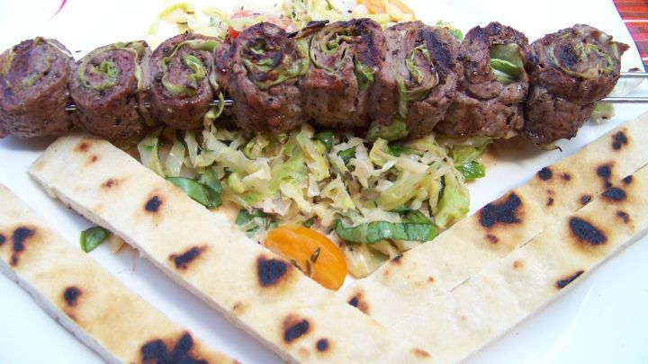 Gegrillte Rinderfilet-Roulade liegt auf einem Bett aus Spitzkohl und wird von knusprigem Pfannenbrot begleitet.