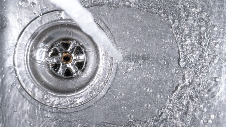 Ein gl&auml;nzender Abfluss wird von Wasser umsp&uuml;lt, w&auml;hrend es im Sp&uuml;lbecken abflie&szlig;t, was die regelm&auml;&szlig;ige Pflege verdeutlicht.