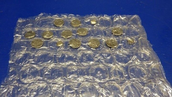 Eine Ansammlung gebrauchter Knopfzellen liegt in einer durchsichtigen Blisterverpackung auf einer blauen Unterlage.