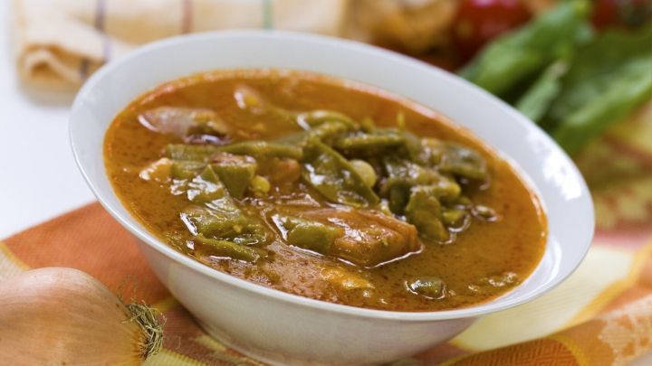 Eine Sch&uuml;ssel Bibbelsches Bohnesupp mit gr&uuml;nen Bohnen und Fleischst&uuml;cken, serviert auf einem bunten Untergrund in der K&uuml;che.