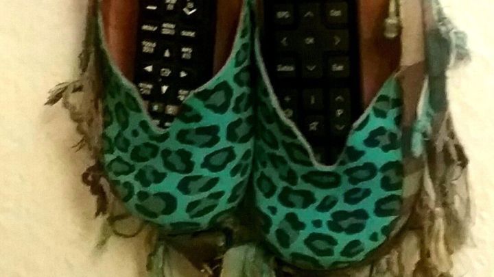 Zwei gr&uuml;ne Clogs mit Leopardenmuster h&auml;ngen an einer Wand, in denen Fernbedienungen platziert sind, um kreativ wiederverwendet zu werden.