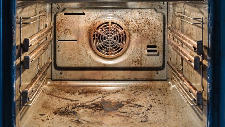 Ein stark verschmutzter Ofen mit extrem eingebrannten Flecken auf den W&auml;nden und dem Boden, sichtbar innen und unordentlich.