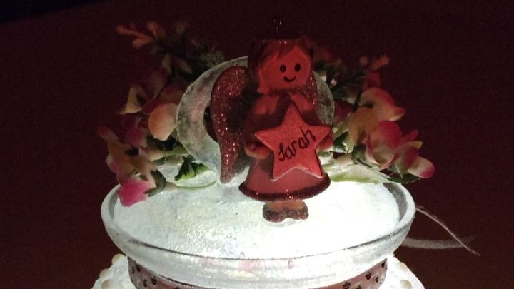 Ein lebendig beleuchtetes Windlicht &bdquo;Fee im Glas&ldquo; steht auf einem Tisch, umgeben von zarten Blumen und einer festlichen Atmosph&auml;re.