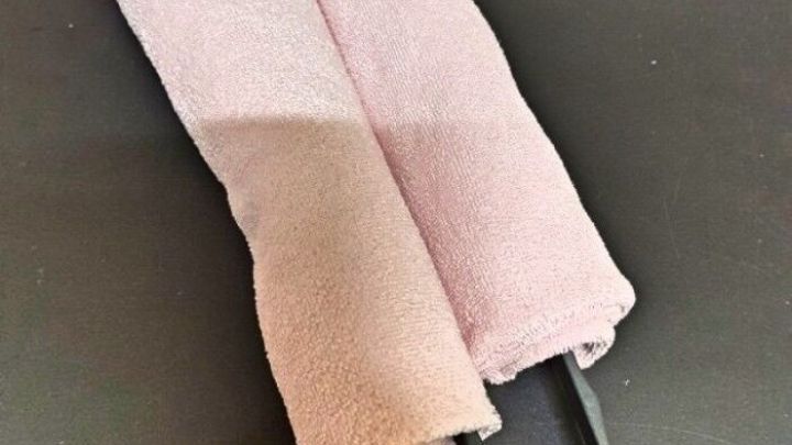 Eine Reinigungsrolle mit zwei Microfasert&uuml;chern liegt auf einer schwarzen Unterlage, bereit zum Abstauben von Lamellen Jalousien.