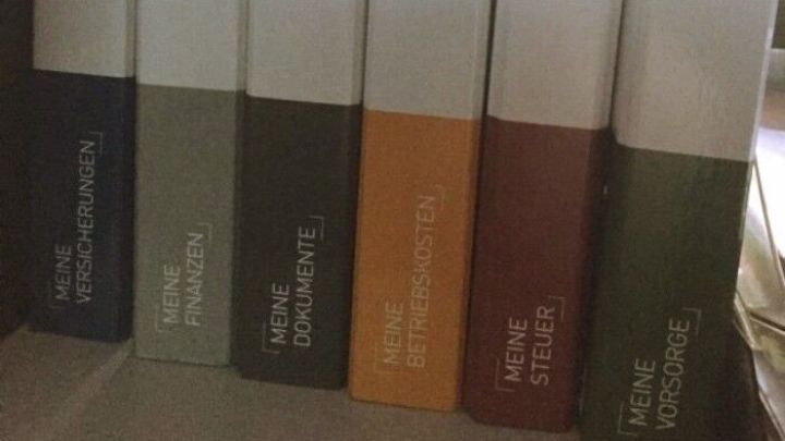 Sechs Ordner stehen ordentlich auf einem Tisch und sind nach Farben sortiert, um das Chaos beim Ordnen von Unterlagen zu beseitigen.