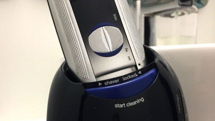 Ein Rasierer steht in einer schwarzen Reinigungskartusche und wird gereinigt, um maximale Hygiene und Effizienz zu gew&auml;hrleisten.