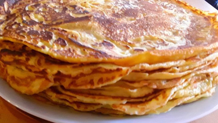 Ein Stapel frisch gebratener Eierpfannkuchen liegt auf einem wei&szlig;en Teller, bereit zum Servieren in einer K&uuml;che.