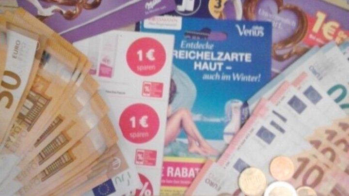 Eine Vielzahl von Geldscheinen, M&uuml;nzen und Coupons liegt auf einer Oberfl&auml;che, die den Akt des Sparens verdeutlicht.