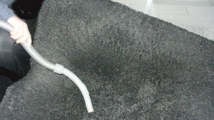 Ein Langflor-Teppich wird mit einem Staubsauger gr&uuml;ndlich gesaugt, um Schmutz und Staub zu entfernen.