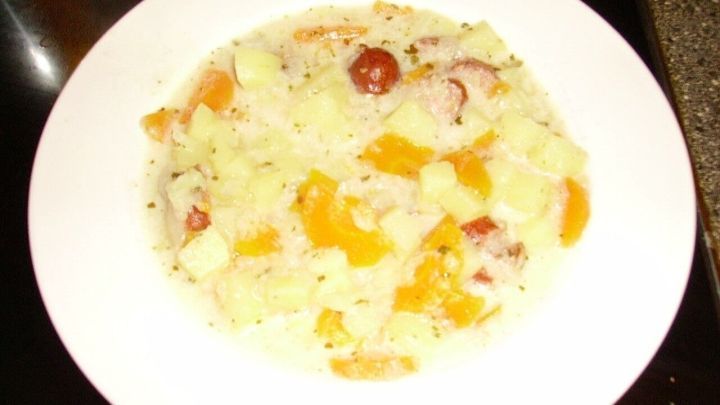 Ein Teller mit holl&auml;ndischem M&ouml;hreneintopf zeigt eine cremige Mischung aus Gem&uuml;se und Kartoffeln auf einem dunklen Tisch.