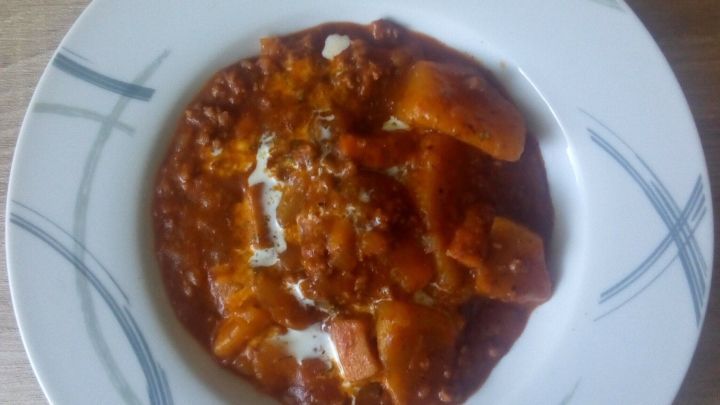 Ein bunter Bauerntopf liegt in einer wei&szlig;en Sch&uuml;ssel mit einem dekorativen Rand und pr&auml;sentiert eine k&ouml;stliche Mischung aus Gem&uuml;se in einer herzhaften So&szlig;e.