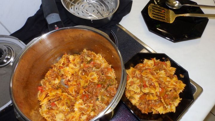 In einem Topf kocht ein Hackfleisch-Gem&uuml;setopf mit Nudeln, daneben eine Sch&uuml;ssel mit der fertigen Mischung auf einer Herdplatte.