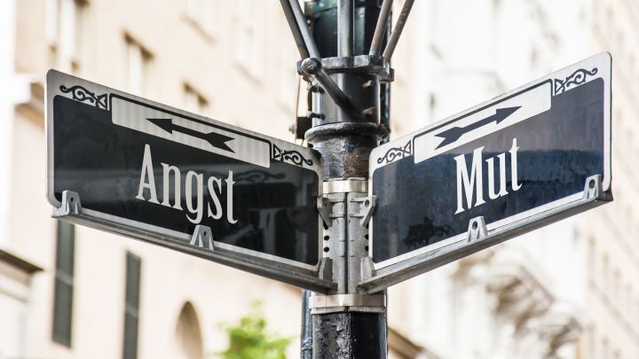 Ein Stra&szlig;enschild zeigt zwei Begriffe: "Angst" und "Mut", welche Zivilcourage symbolisieren und wichtige Entscheidungen im Leben darstellen.