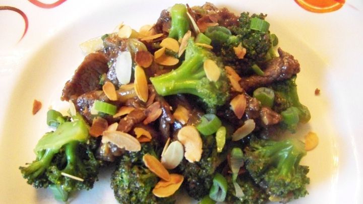 Rinderfilet mit Brokkoli und Mandeln liegt appetitlich angerichtet auf einem Teller, umgeben von einer dekorativen Randgestaltung.